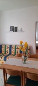 a table with a couch and a vase with yellow flowers at Apartmani Nikica in Drage