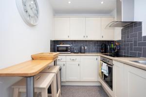 a kitchen with white cabinets and a clock on the wall at ALTIDO Elegant New Town Flat near Princes Street in Edinburgh