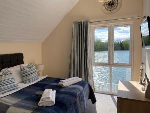 a bedroom with a bed and a large window at Cotswolds Lakeside Lodge - Nesbitt's Nest in South Cerney
