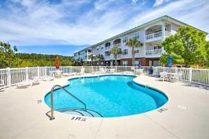 a swimming pool at a resort with chairs and a building at Little River Condo with Pool Less Than 6 Mi to Beach! in Little River
