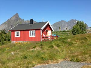 une maison rouge sur une colline avec des montagnes en arrière-plan dans l'établissement Rorbua på Toppøya, à Reine