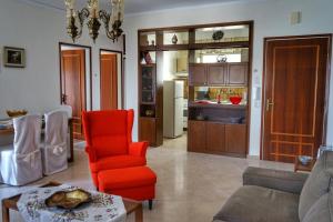 a living room with a red chair and a kitchen at Liana`s apartment in Paleo Tsifliki