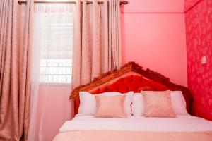 a bedroom with a bed with a red headboard and a window at Dondoo's Paradise- Perfect Vacation Home in Kilifi