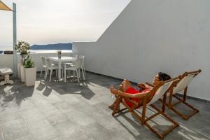 a woman sitting in a chair on a balcony at Akron Cliff Suite in Fira