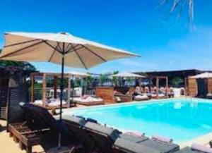 a swimming pool with chairs and an umbrella at APPARTEMENT DUPLEX PORTICCIO Centre in Porticcio