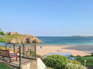 a view of a beach with a bench and the ocean at Seashells in Tenby