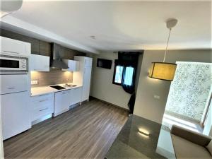 una cocina con armarios blancos y electrodomésticos blancos en Apartamentos Sol del Prior en Úbeda