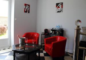 a living room with two red chairs and a table at Le Potier Jovial in Ger