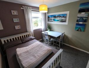 a bedroom with a bed and a table and a window at Hampton House Book-Inn in Northampton