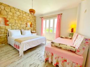 a bedroom with two beds and a stone wall at Kesre Hotel in Alaçatı