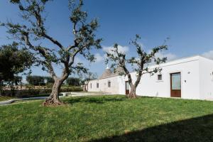 two trees in a yard next to a white building at Mandolario Trulli Resort in Martina Franca