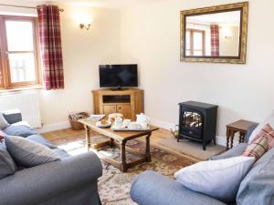 a living room with a couch and a table and a tv at The Cider House in Leominster