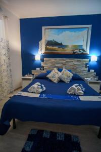 Un dormitorio con una cama azul con una pintura en la pared en La casa del pescatore, en Oliveri