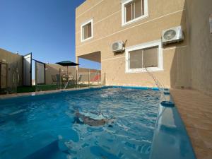 a swimming pool in front of a building at فيلا أمواج الشاطىء Amoaj beach in Rayyis