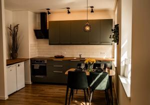 a kitchen with green cabinets and a table with chairs at MOOD Apartamenti Kuldīgā in Kuldīga
