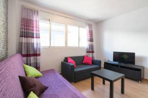 sala de estar con sofá púrpura y TV en Apartamento Postigos, en Málaga