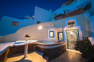 un bâtiment avec bain à remous sur un patio la nuit dans l'établissement Santorini Paradise Cave Houses, à Oia