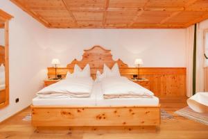 a bedroom with a wooden bed with white pillows at Gschwendtnerhof App8 Fuß in Aschau im Chiemgau