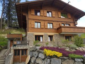 a wooden house with a stone wall in front of it at Chalet Grüneggli in Adelboden