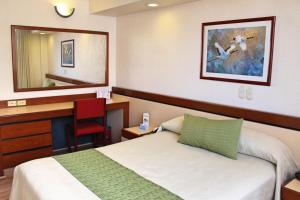 Habitación de hotel con cama, escritorio y espejo. en Hotel Manalba en Ciudad de México