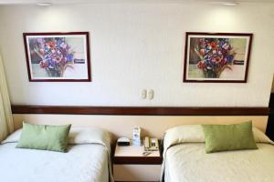 two beds in a hotel room with flowers on the wall at Hotel Manalba in Mexico City