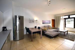 Una cocina y una sala de estar con refrigerador y una mesa. en Beach Adeje Apartment, en Adeje