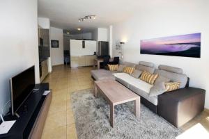 Una sala de estar con un sofá, una mesa y un televisor. en Beach Adeje Apartment, en Adeje