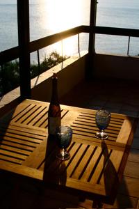 a wooden table with a bottle and two glasses on a balcony at Sea Front in Milina