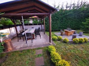 un pabellón de madera con una mesa y sillas en un patio en Máté Holiday House, en Gyula