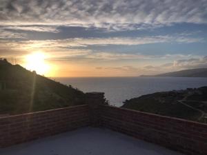 a sunset over the ocean from a brick wall at Grand Seaview Apartments in Ksamil