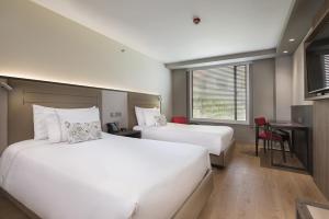 a hotel room with two beds and a desk at Hotel Habitel Prime in Bogotá