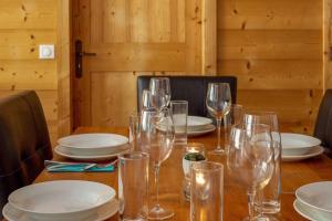 a wooden table with wine glasses and plates on it at Appartement vue sur les montagnes Suisses in Vallorcine