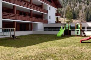 a playground in front of a building with a slide at Appartement vue sur les montagnes Suisses in Vallorcine