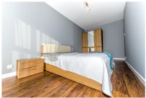 een slaapkamer met een bed en een houten vloer bij Apartament 75,143 Porta Mare in Dziwnówek