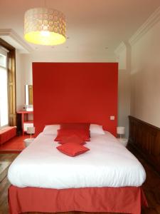 a bedroom with a large white bed with a red headboard at La Maison d'Adelaïde in Saint-Flour