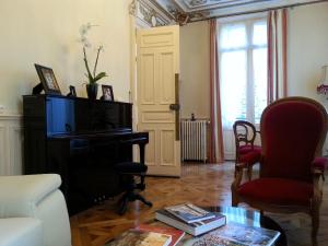 a living room with a table and a piano at La Maison d'Adelaïde Chambres d'hôtes in Saint-Flour