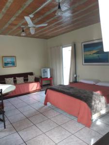 a bedroom with two beds and a table and a tv at Pousada da Barra in Barra de São João