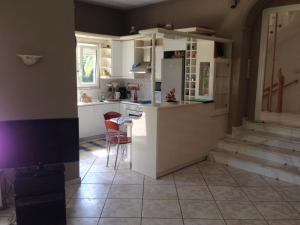 a kitchen with white cabinets and a counter and chairs at House with Garden in Nea Peramos