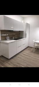 uma cozinha com armários brancos, um lavatório e uma mesa em Appartamento il Torchio em Lecco