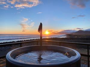 a hot tub on the beach with the sunset in the background at Marbakki Luxury Ocean Retreat in Budhir