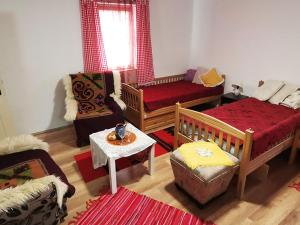 a living room with two beds and a table at "Pivnica i smestaj Jovanovic"- Rogljevacke pivnice in Rogljevo