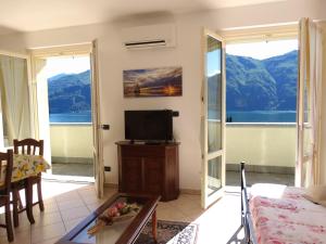een woonkamer met een televisie en een balkon bij Casavalery Appartamento monolocale con vista lago in Bellagio