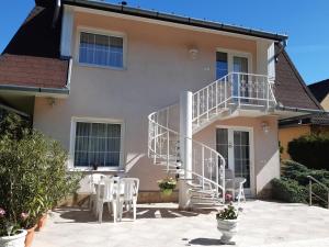 a house with white stairs and tables and chairs at Fődi apartman in Zalakaros