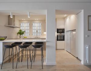 a kitchen with white walls and bar stools at Itsas aire - Basquenjoy in Hondarribia