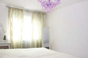 ein Schlafzimmer mit einem weißen Bett und einem lila Kronleuchter in der Unterkunft Apartment aPriori-Baden-Baden in Baden-Baden