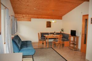 a living room with a blue couch and a table at Ferienwohnungen Hell in Uderns