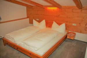 a bed in a wooden room with white pillows at Ferienwohnungen Hell in Uderns