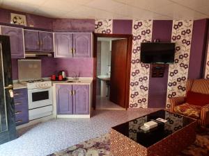 una cocina con armarios morados y TV. en La Fontain Resort Al Shafa en Al Shafa