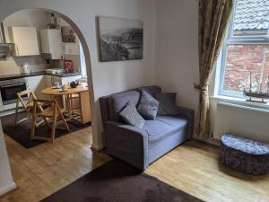 a living room with a couch and a kitchen at Endeavour Cottage Whitby sleeps 6 in Whitby