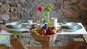 a table with a basket of fruit and a vase of flowers at Una casa tra gli alberi in Tresivio